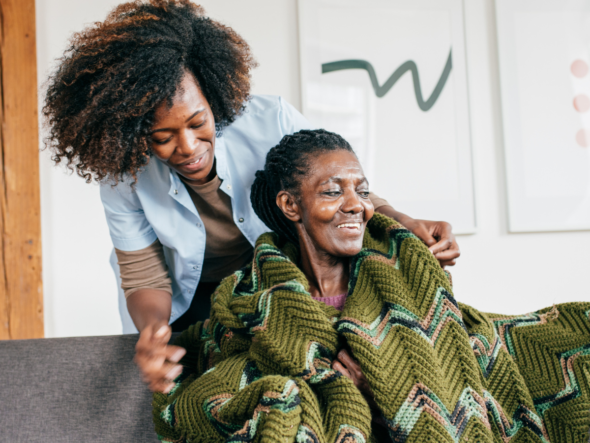 am-i-a-caregiver woman wrapping elderly mother in blanket while being a caregiver